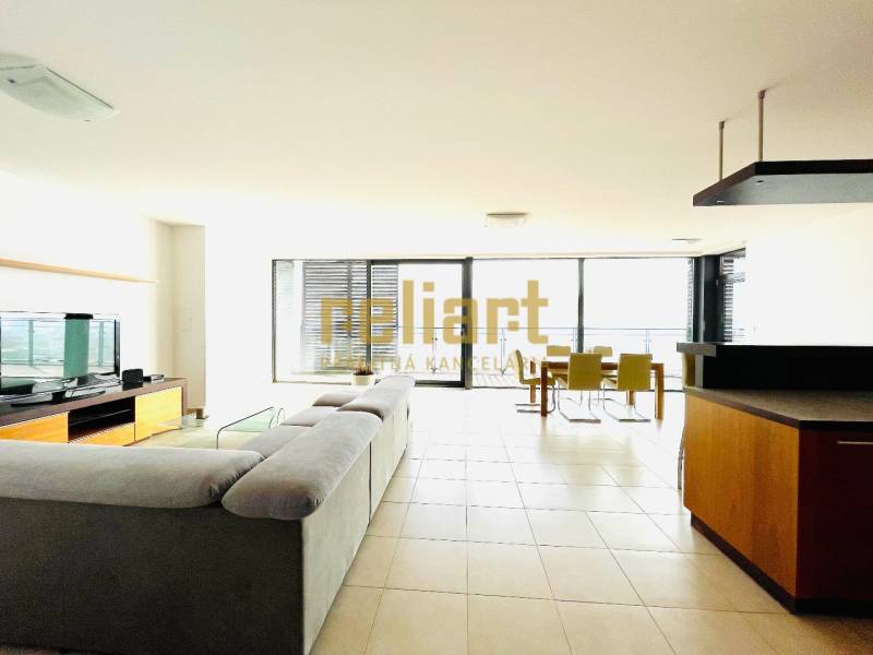 Koliba:Na prenájom 4i, lux. byt,terasa, bazén/eng.text inside - Obývačka s veľkou sedačkou v 4-izbovom byte, hladká podlaha, presklené steny.