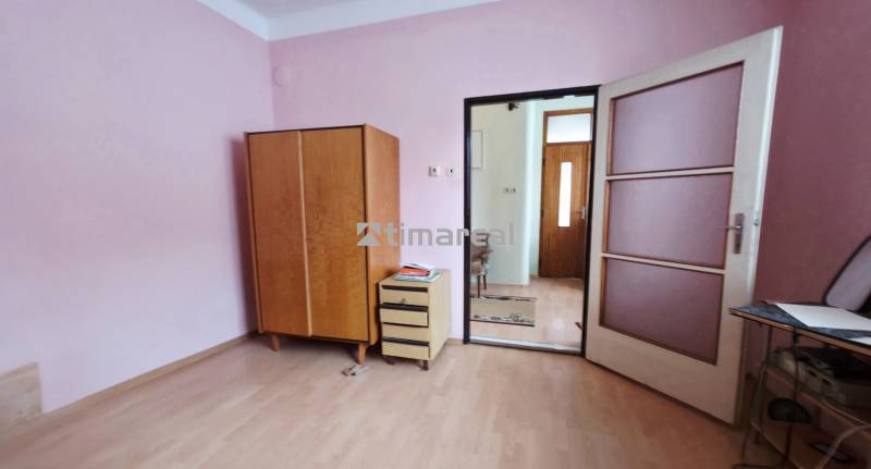 4i rodinný dom s garážou, 8á pozemok s vlastnou studňou, Križovany - Izba v rodinnom dome s ružovými stenami, podlahou s dreveným dekorom a nábytkom.