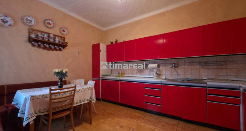 4i rodinný dom s garážou, 8á pozemok s vlastnou studňou, Križovany - Kuchyňa v rodinnom dome s červenou linkou a jedálenským stolom, dekorovaná keramickými taniermi.