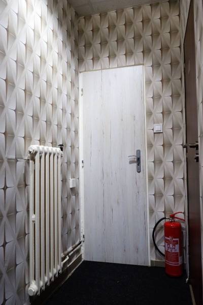 Kaviareň v Top lokalite mesta Šaľa na predaj - Obchodné priestory s geometrickou tapetou, dverami, radiátorom a hasiacim prístrojom.