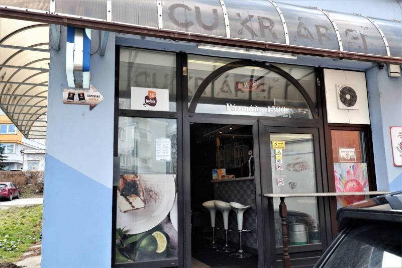 Kaviareň v Top lokalite mesta Šaľa na predaj - Obchodné priestory v Šali s veľkým oknom, dreveným dekorom a bielymi stoličkami.