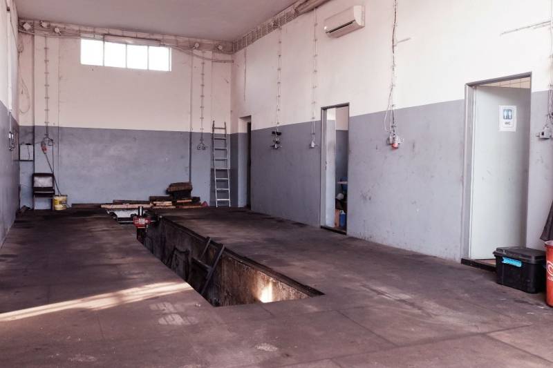 Prevádzková budova-AUTOSERVIS na predaj vo Veľkých Úľanoch - Oprava áut vo výrobných priestoroch s podlahou s dreveným dekorom a servisnou jamou.