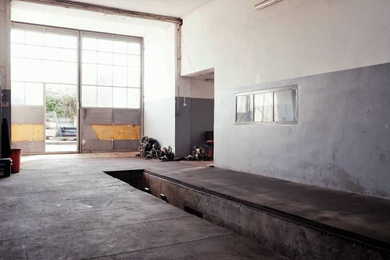 Prevádzková budova-AUTOSERVIS na predaj vo Veľkých Úľanoch - Výrobné priestory s veľkými oknami, garážovou bránou a podlahou s dreveným dekorom.