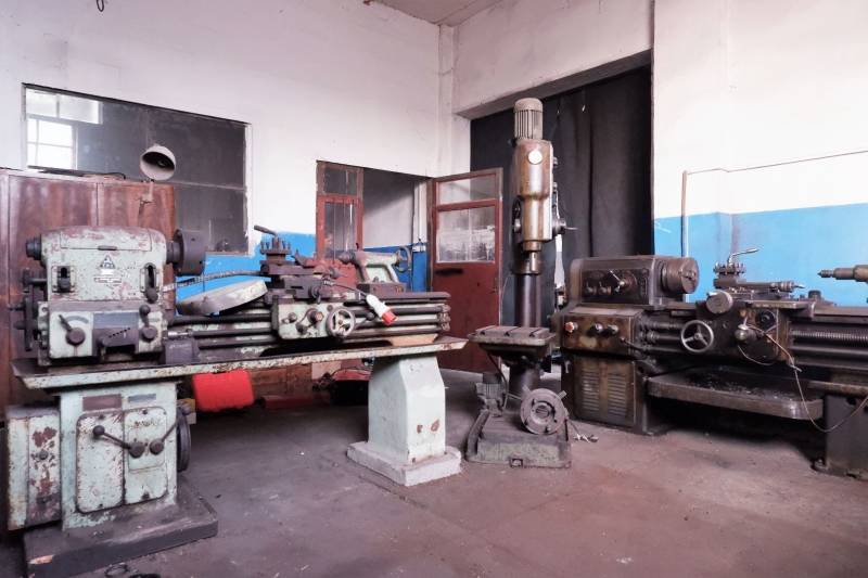 Prevádzková budova-AUTOSERVIS na predaj vo Veľkých Úľanoch - Výrobné priestory so starými strojmi a neomietnutými stenami, podlaha s dreveným dekorom.