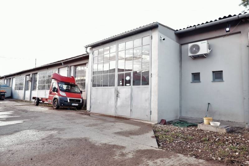 Prevádzková budova-AUTOSERVIS na predaj vo Veľkých Úľanoch - Výrobné priestory vo Veľkých Úľanoch s plechovými bránami a červeným autom.