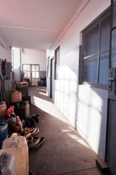 Prevádzková budova-AUTOSERVIS na predaj vo Veľkých Úľanoch - Úzky chodba vo výrobných priestoroch s uskladnenými nádobami a náradím.