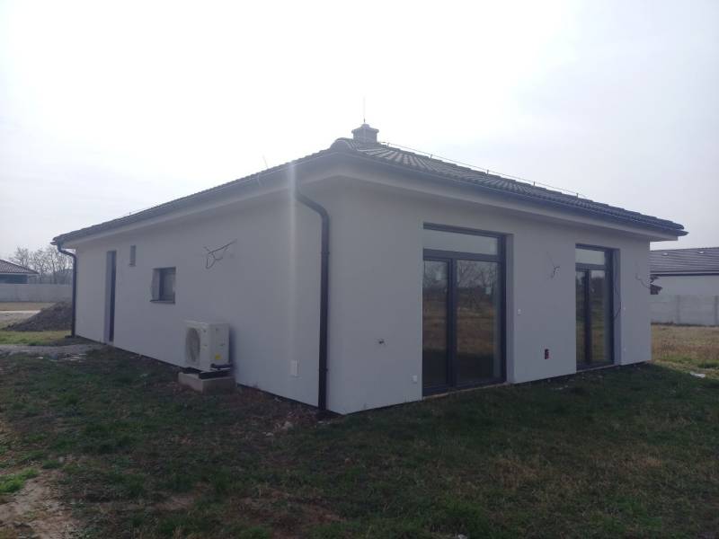 POSLEDNÁ Novostavba 4-izb rodinného domu v lukratívnej časti mesta - Rodinný dom v Galante s bielou fasádou a oknami so sklobetónom.