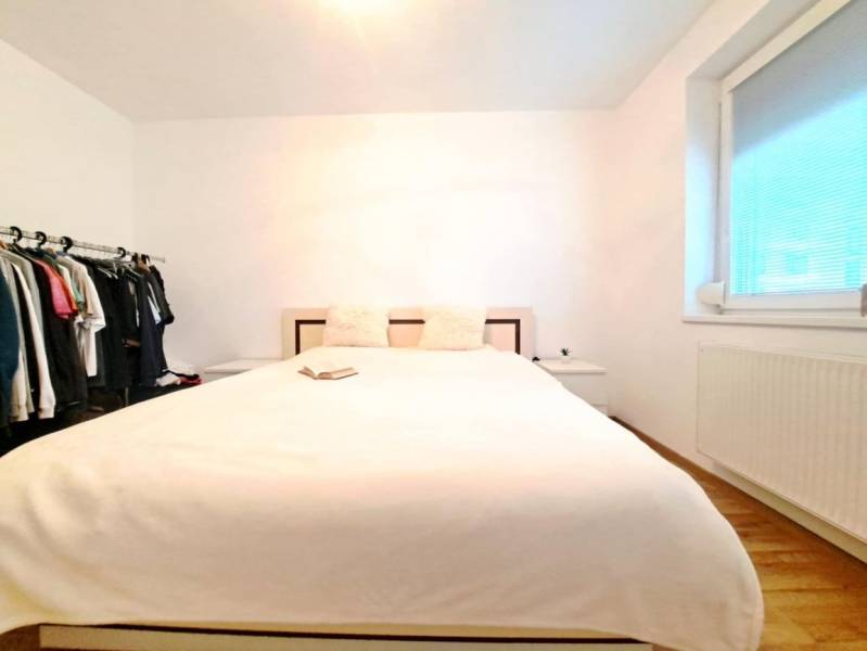 Miesto, kde sa budete cítiť doma–2-izbový byt na sídlisku West-Galana - Spálňa v 2-izbovom byte s posteľou, otvoreným šatníkom a podlahou s dreveným dekorom.