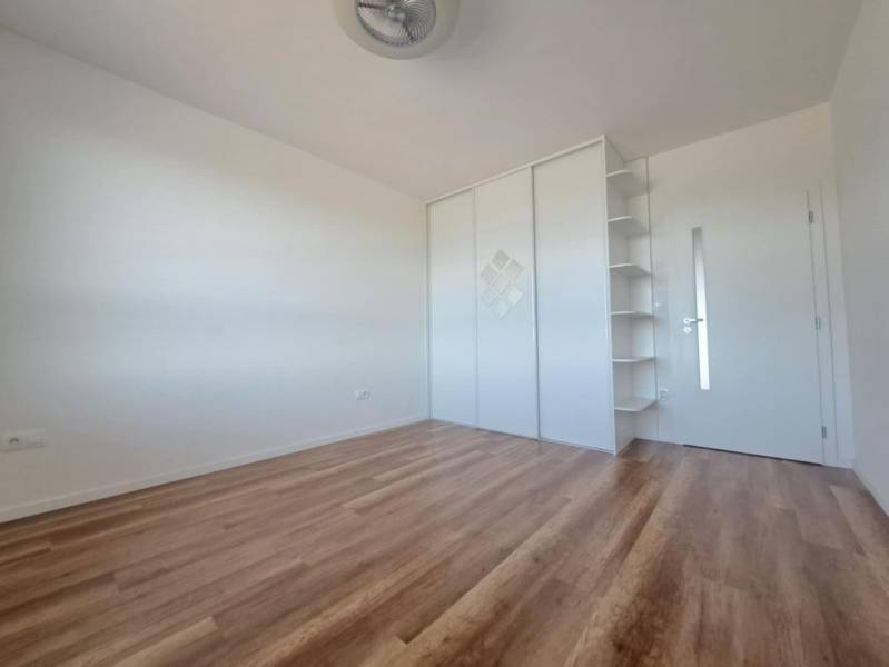 REZERVOVANÝ! Nová cena! Moderný 2-izbový byt – Galanta, sídlisko West - Izba v 2-izbovom byte s podlahou s dreveným dekorom, bielou skriňou a policami.