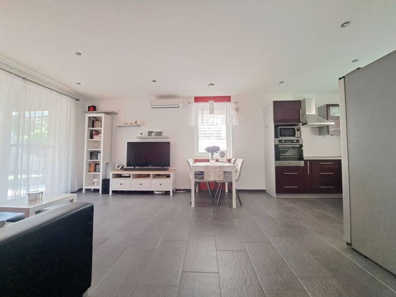 Predvianočná zľava! Na predaj krásny 4izb dom v obci Čierny Brod  - Obývacia izba s TV, kuchyňou a jedálenským stolom, podlaha s dreveným dekorom.