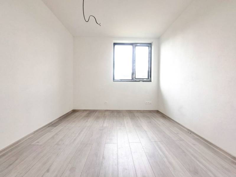 Priestranné novostavby 4-izbových rodinných domov v meste Šaľa - Prázdna miestnosť s podlahou s dreveným dekorom a oknom v rodinnom dome.