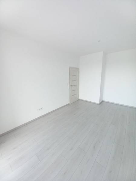 SKOLAUDOVANÉ! Novostavba 2-3 izbových bytov s pozemkom Richtárske pole - Miestnosť v 2-izbovom byte s bielymi stenami a podlahou s dreveným dekorom.