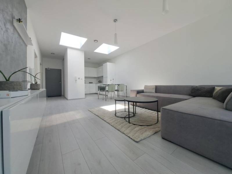 SKOLAUDOVANÉ! Novostavba 2-3 izbových bytov s pozemkom Richtárske pole - Obývacia izba s pohovkou, podlahou s dreveným dekorom a jedálenským stolom v 2-izbovom byte.