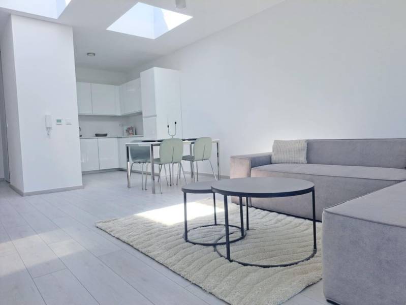 SKOLAUDOVANÉ! Novostavba 2-3 izbových bytov s pozemkom Richtárske pole - Svetlá obývačka s kuchyňou, pohovkou a podlahou s dreveným dekorom v 2-izbovom byte.