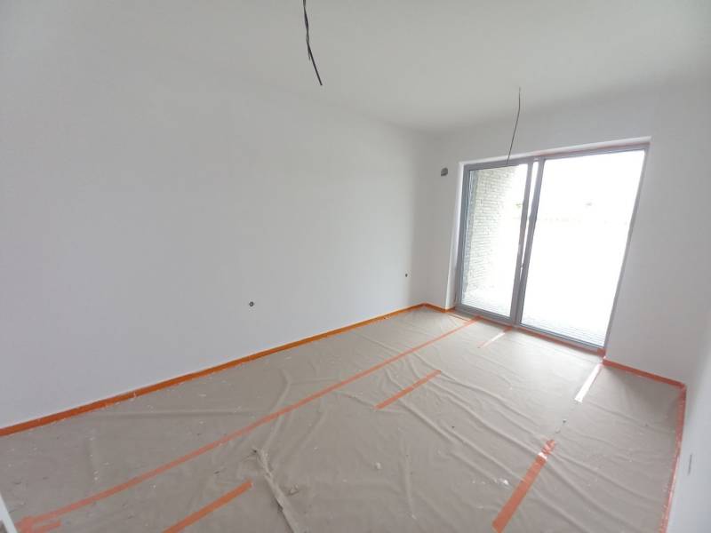 SKOLAUDOVANÉ! Posledné voľné obchodné priestory na predaj v novostavbe - Obchodné priestory s veľkým oknom, biela maľovka, podlaha s dreveným dekorom prikrytá fóliou.