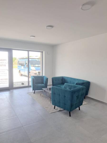 SKOLAUDOVANÉ! Posledné voľné obchodné priestory na predaj v novostavbe - Obchodné priestory s tyrkysovým sedením, šedou podlahou a veľkým oknom.