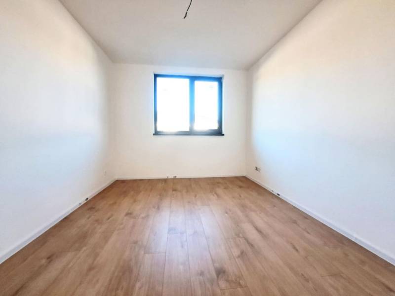 REZERVOVANÉ! Posledná novostavba 4-izbového dvojdomu v štandarde - Výhľad na izbu s bielymi stenami a podlahou s dreveným dekorom v rodinnom dome.