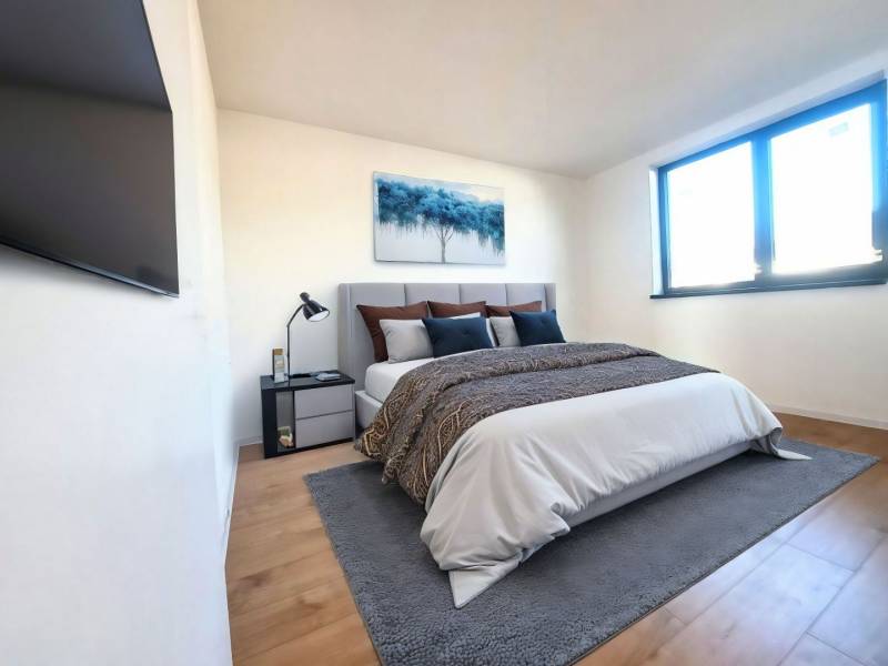 REZERVOVANÉ! Posledná novostavba 4-izbového dvojdomu v štandarde - Spálňa v rodinnom dome s posteľou, obrazom, TV a podlahou s dreveným dekorom.