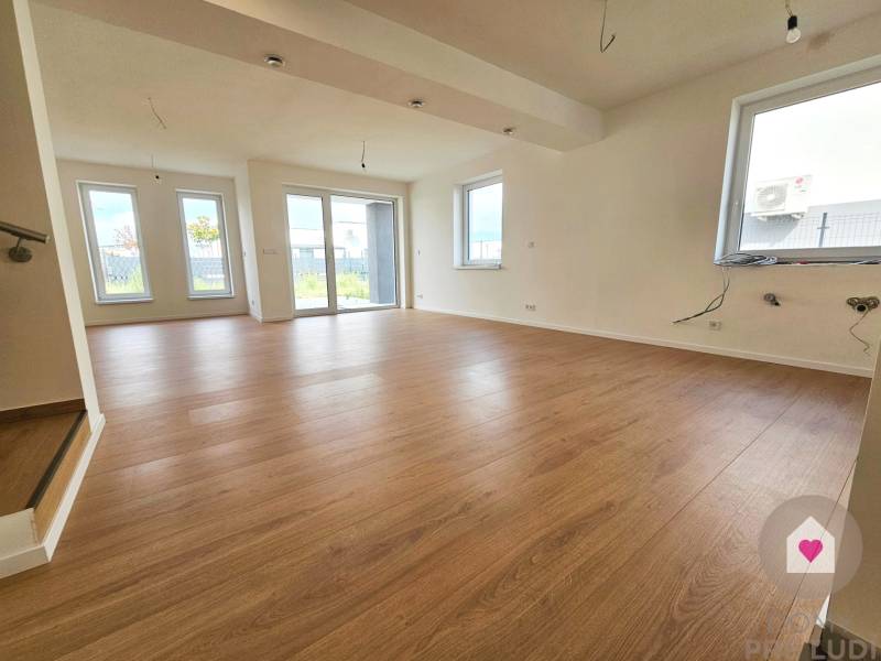 VEĽKORYSO RIEŠENÝ 4 izbový RD-128 m2 S TEP. ČERPADLOM, POZEMOK 405 m2 - Priestranná obývačka v rodinnom dome s podlahou s dreveným dekorom.