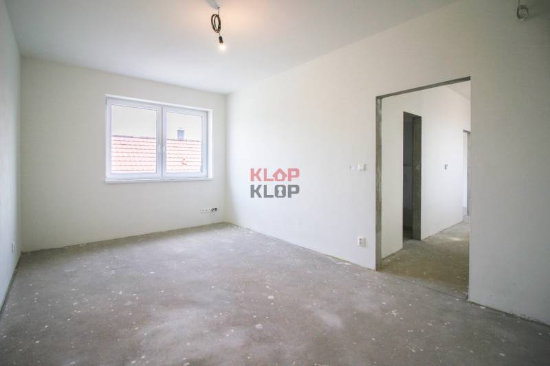 Kúpte si MODERNÚ NOVOSTAVBU 5i RD pri SENCI s MOŽNOSŤOU VÝMENY za BYT - Prázdna miestnosť s betónovou podlahou, oknom a otvorom do chodby v rodinnom dome.