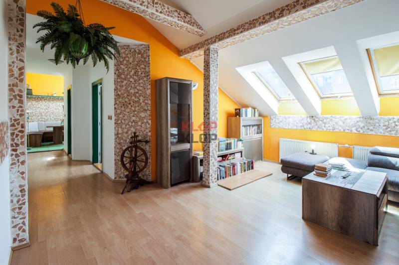 Kúpte si veľký PODKROVNÝ 4i BYT so ZÁHRADOU a PIVNICOU v Starom meste - Podkrovný interiér 4-izbového bytu s drevenou podlahou, knihovňou a svetlými stenami.