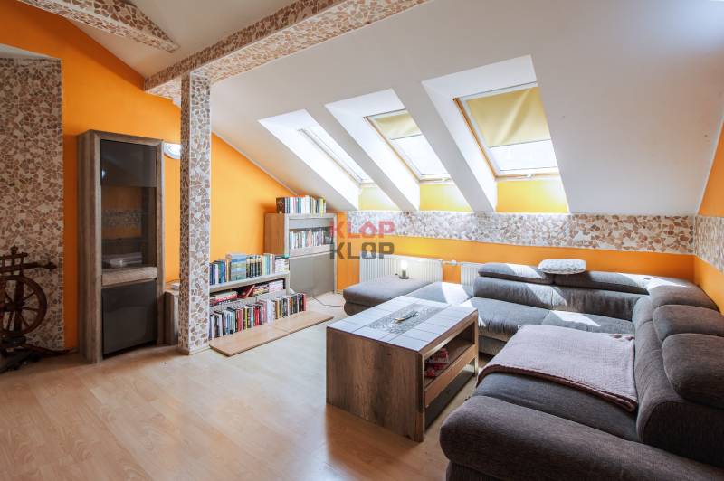 Kúpte si veľký PODKROVNÝ 4i BYT so ZÁHRADOU a PIVNICOU v Starom meste - Podkrovná obývacia izba v 4-izbovom byte s oranžovými stenami a sedačkou.