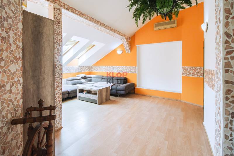 Kúpte si veľký PODKROVNÝ 4i BYT so ZÁHRADOU a PIVNICOU v Starom meste - Obývačka v 4-izbovom byte s oranžovou stenou, šikmým stropom a rohovou sedačkou.