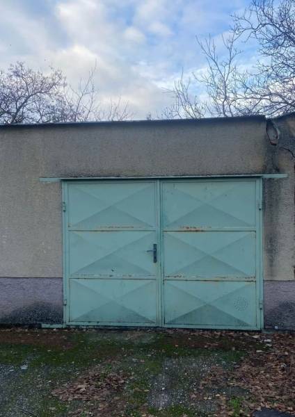  Na predaj  3i byt s vlastnou garážou neďaleko Šale - Garážová brána so svetlomodrými dverami a opadané listy v Seliciach.