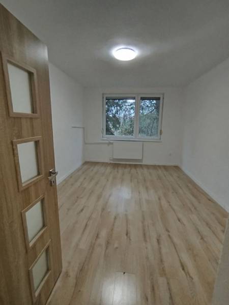  Na predaj  3i byt s vlastnou garážou neďaleko Šale - Priestranná izba v 3-izbovom byte s podlahou s dreveným dekorom a veľkým oknom.