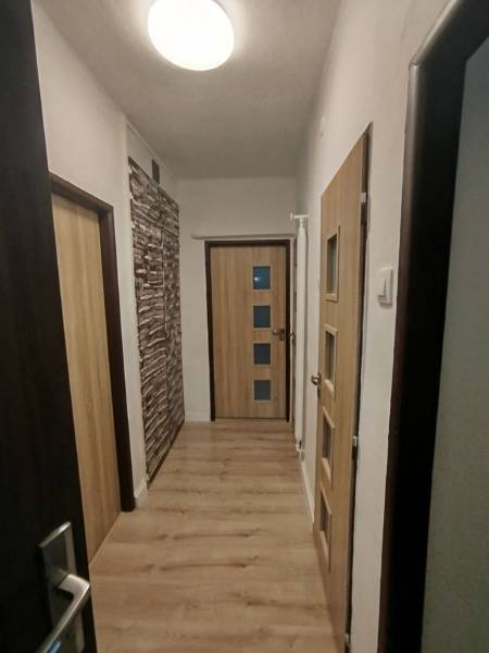  Na predaj  3i byt s vlastnou garážou neďaleko Šale - Chodba so svetlou podlahou a drevenými dverami v 3-izbovom byte.
