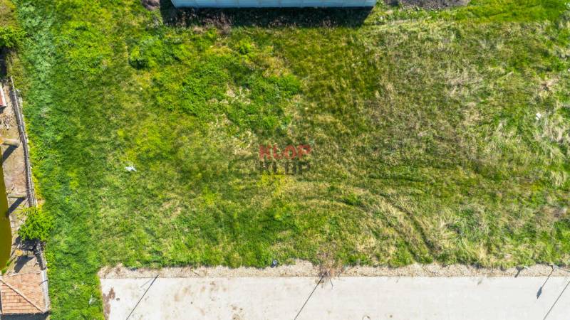 Kúpte si SVETLÝ, TICHÝ stavebný pozemok s IS a OPTIMÁLNOU ROZLOHOU  - Zelený pozemok vhodný na bývanie, ohraničený betónovým plotom a spevnenou cestou.