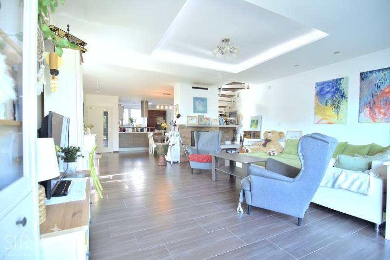 HROZNOVÁ, 4-i RD, 161 m2 – novostavba, krb, klíma, krásna záhrada - Obývacia izba v rodinnom dome s podlahou s dreveným dekorom, pohodlným sedením a schodiskom.