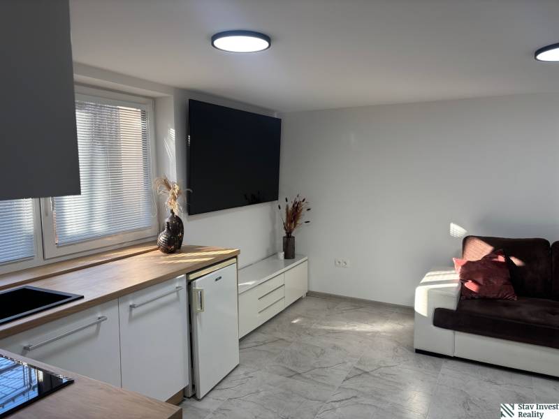 Dom za cenu bytu- komplet prerobený RD 3 izb. Blatné  - Obývacia miestnosť v rodinnom dome s bielou kuchynskou linkou a tmavohnedou pohovkou.