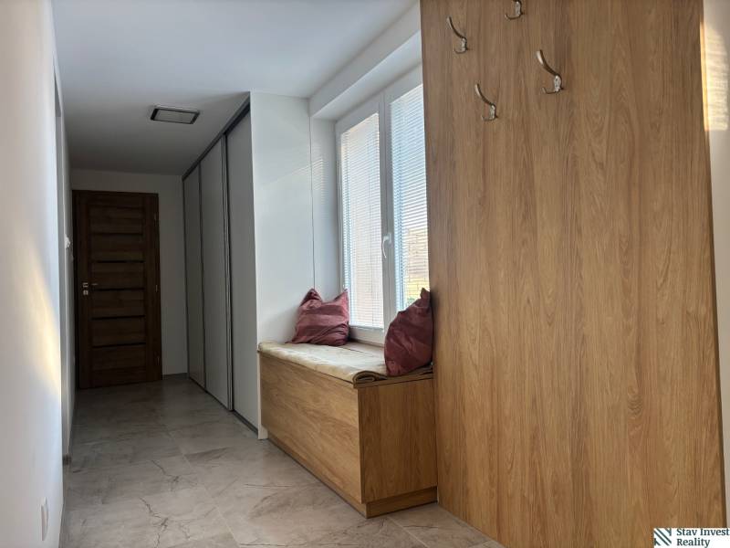 Dom za cenu bytu- komplet prerobený RD 3 izb. Blatné  - Chodba v rodinnom dome s vešiakmi a sedením s poduškou, podlaha s dreveným dekorom.