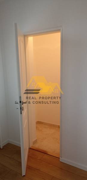 Prerobený 2 izbový byt s balkónom v Nových Zámkoch - Interiér 2-izbového bytu s otvorenými dverami a podlahou s dreveným dekorom.