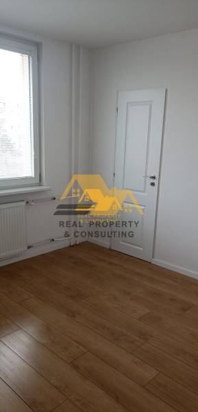 Prerobený 2 izbový byt s balkónom v Nových Zámkoch - Pohľad na izbu s bielymi stenami a podlahou s dreveným dekorom v 2-izbovom byte.