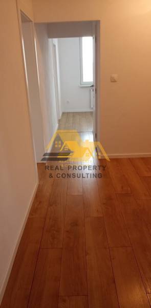 Prerobený 2 izbový byt s balkónom v Nových Zámkoch - Chodba s podlahou s dreveným dekorom v 2-izbovom byte, neutrálne steny.