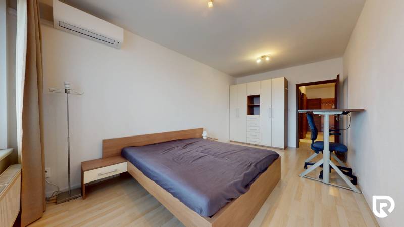 | Svetlý priestranný 2 izbový byt | parkovanie | REZERVOVANÝ - Spálňa v 2-izbovom byte s veľkou posteľou, podlahou s dreveným dekorom a skriňou.