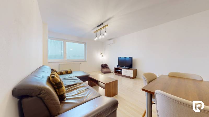 | Svetlý priestranný 2 izbový byt | parkovanie | REZERVOVANÝ - Obývacia izba s pohovkou, televíziou a podlahou s dreveným dekorom v 2-izbovom byte.