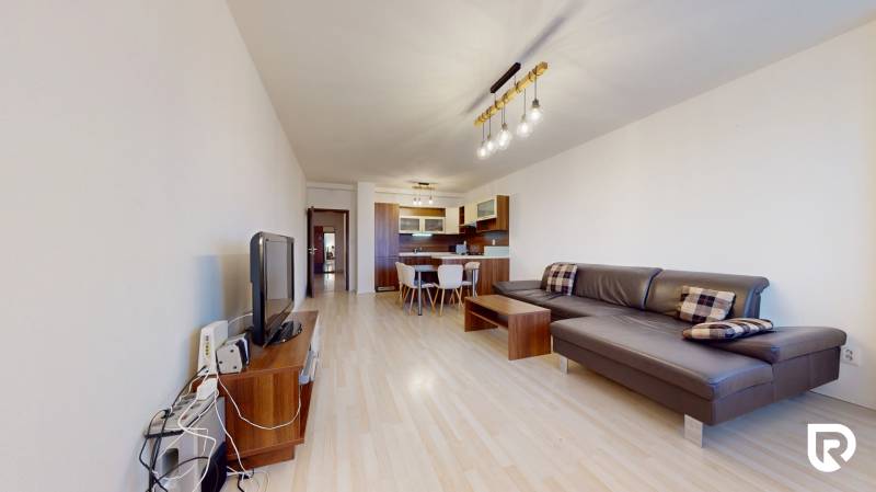 | Svetlý priestranný 2 izbový byt | parkovanie | REZERVOVANÝ - Obývacia izba v 2-izbovom byte s podlahou s dreveným dekorom a pohodlnou sedačkou.