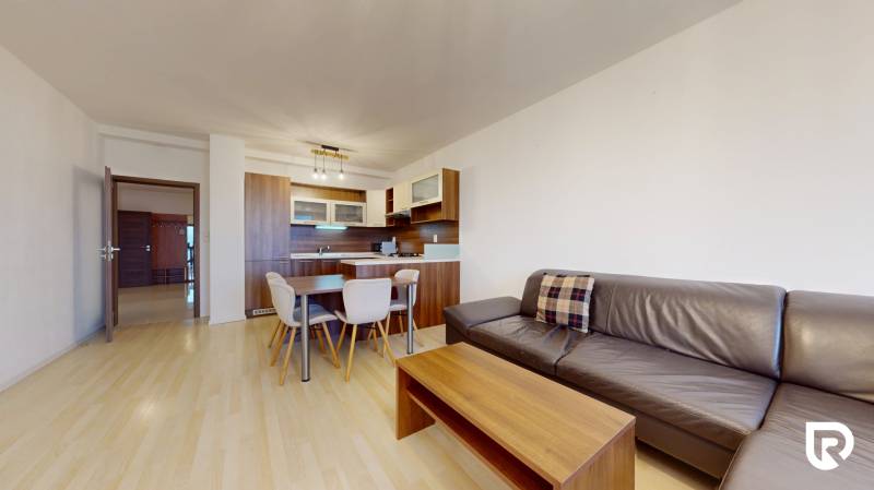 | Svetlý priestranný 2 izbový byt | parkovanie | REZERVOVANÝ - Obývacia izba v 2-izbovom byte s podlahou s dreveným dekorom a pohodlnou pohovkou.