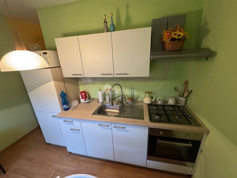 PREDAJ EXKLUZÍVNE: 1i byt s balk.; 41,02 m2; POPRAD; 124.200€ - Kuchyňa v 1-izbovom byte s bielymi skrinkami a podlahou s dreveným dekorom.