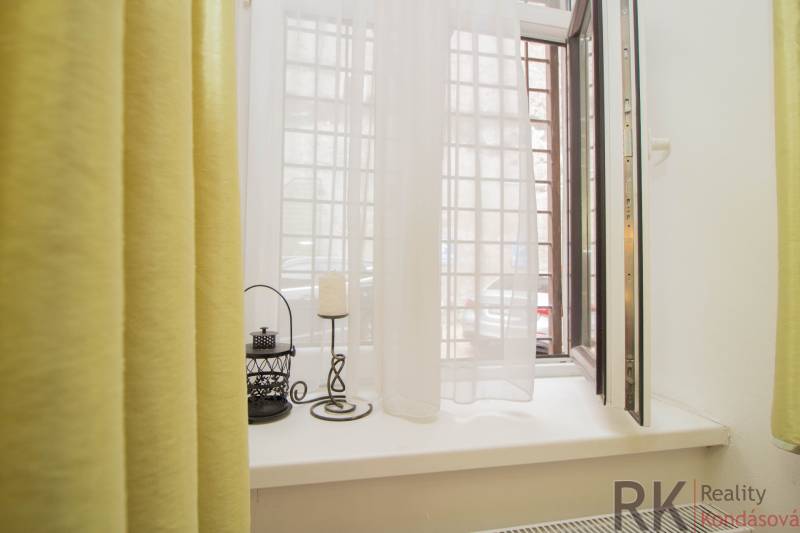 Centrum Košíc - 2-izb.tehlový byt s parkovaním vo dvore - Otvorené okno v 2-izbovom byte so závesmi a dekoráciami na parapete.