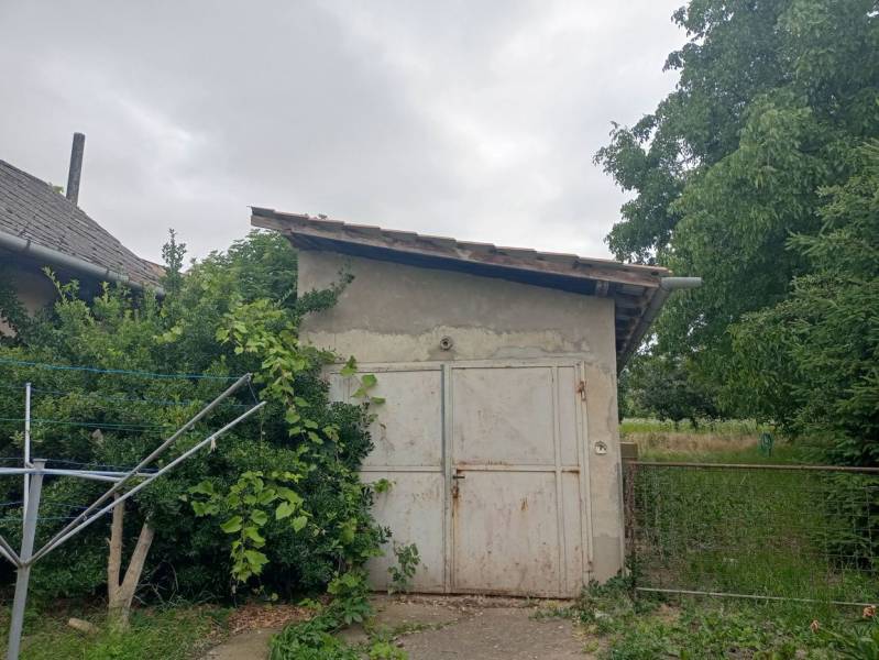 Predám Rodinný dom v Strekove - Rodinný dom v Strekove s malým prístreškom obklopený zeleňou a stromami.