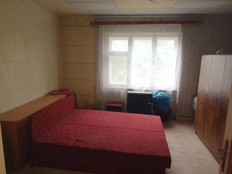 Predám Rodinný dom v Strekove - Spálňa v rodinnom dome s jednoduchým nábytkom a červenou posteľou.