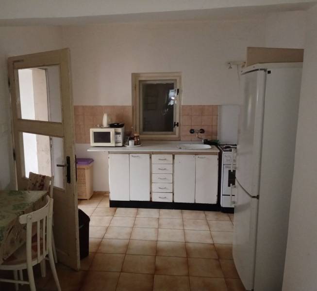 Predám Rodinný dom v Strekove - Kuchyňa v rodinnom dome s bielymi skrinkami, mikrovlnkou a chladničkou.