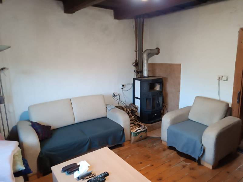 Samota Nová Baňa – Štále s hospodárskymi stavbami  - Rodinný dom s drevenou podlahou, pohovkou, kreslom a krbovými kachľami na drevo.