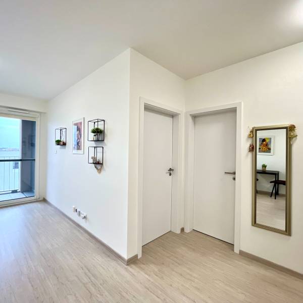 Súčasný 2-izbový byt v novostavbe – Matadorka  - Dvojgarsónka s podlahou s dreveným dekorom, biela stena, balkónové dvere a zrkadlo.