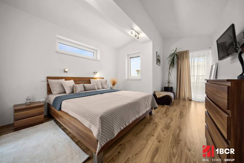 MODERNÝ 5-IZBOVÝ RODINNÝ DOM V ČUNOVE: 180m2 KOMFORTU A TICHA - Spálňa v rodinnom dome s posteľou, dekoratívnymi prvkami a podlahou s dreveným dekorom.