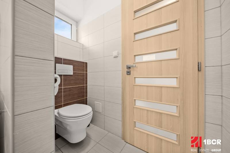 MODERNÝ 5-IZBOVÝ RODINNÝ DOM V ČUNOVE: 180m2 KOMFORTU A TICHA - Toaleta v rodinnom dome so svetlými obkladmi a dverami s vertikálnymi pruhmi.